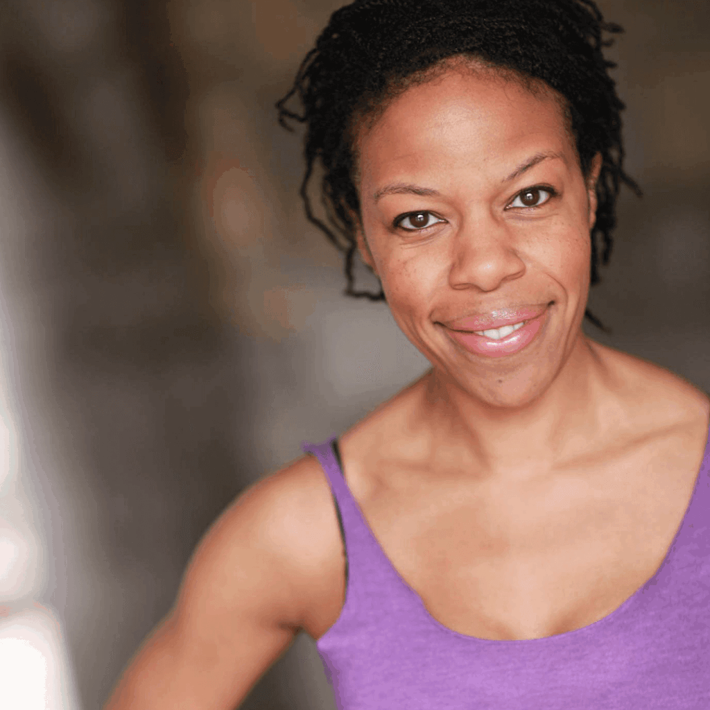 The Freeman Studio Woman with braided hair smiles slightly, wearing a purple tank top. The blurred background draws attention to her face and upper body, reflecting the poise often seen in students from The Freeman Studio or Toronto Acting Studio. New York & Toronto Acting Studio