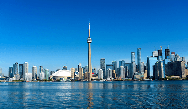 The Freeman Studio Toronto skyline with the CN Tower and modern high-rise buildings, viewed from across the water under a clear blue sky. New York & Toronto Acting Studio