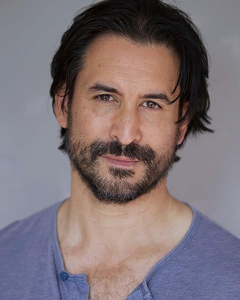 The Freeman Studio A man with dark hair and a beard, wearing a blue-gray henley shirt, looks at the camera against a plain gray background. New York & Toronto Acting Studio